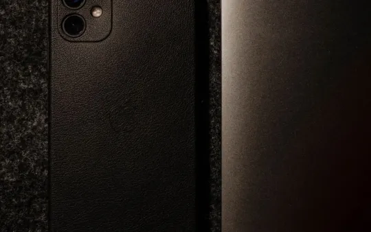 Celular e notebook sobre mesa escura